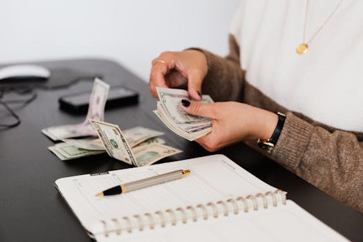 pexels-photo-4475523-4475523-1 Close-up of person counting cash with notepad on desk, indicating financial tasks.